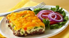 a white plate topped with an omelet next to a salad on a yellow table cloth