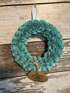 a wreath made out of rolled paper sitting on top of a wooden table next to a tag