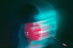 a blurry image of a woman's face with red and blue light coming from her eyes