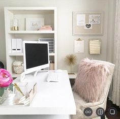 a white desk with a computer on it and a pink flower in front of the monitor