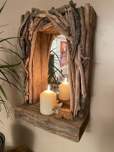 a mirror made out of driftwood with two lit candles on the shelf next to it