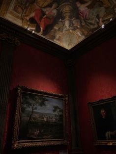 two paintings hanging on the wall in a red room