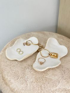 two pieces of jewelry sitting on top of a stone table next to a white wall