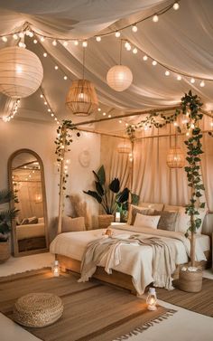 a bedroom decorated in white with lights and greenery on the ceiling, along with a canopy bed