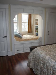 a bedroom with a bed and built in bookshelves on either side of the window