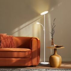 a living room with an orange couch, lamp and rug on the floor in front of it