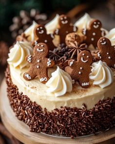 a cake with frosting and decorated gingerbreads is on a wooden platter