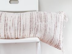 a pillow sitting on top of a white chair next to a wooden frame and wall