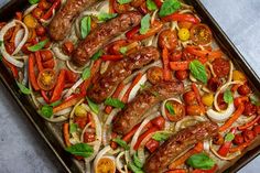 a pan filled with sausages, peppers and onions