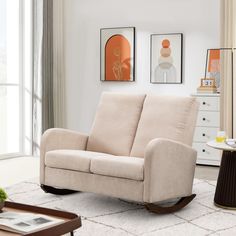 a living room with a rocking chair, table and pictures on the wall above it