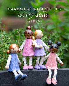 three little dolls are standing next to each other in front of some bushes and plants