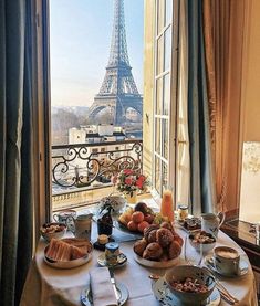 the table is set for breakfast in front of the window overlooking the eiffel tower