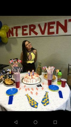 a woman standing in front of a table with cake and cupcakes on it