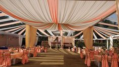 the inside of a tent with tables and chairs set up for a formal function or wedding