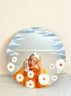 a woman taking a selfie in front of a mirror with daisies on it