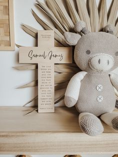 a stuffed animal sitting on top of a wooden shelf next to a cross and plaque