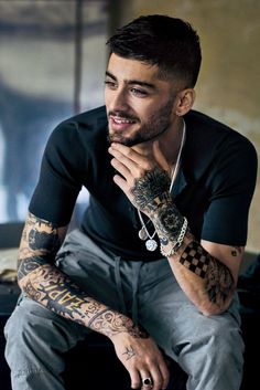 a man with tattoos on his arms sitting down