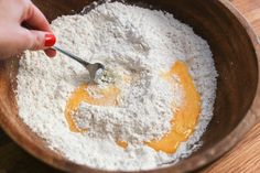 a person mixing ingredients in a wooden bowl