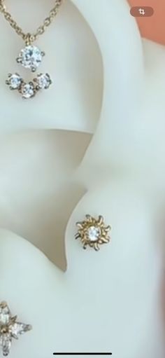 three pieces of jewelry sitting on top of a white object with gold chains and diamonds