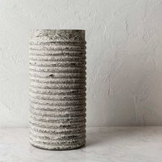 a large gray vase sitting on top of a white counter next to a brick wall