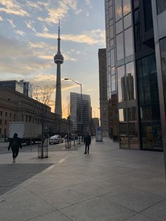 people are walking on the sidewalk in front of tall buildings and a sky scraper