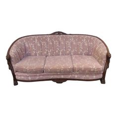 an old fashioned couch with pink fabric and wood trimmings on the armrests