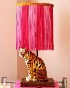 a tiger lamp sitting on top of a table next to a pink cloth covered shade