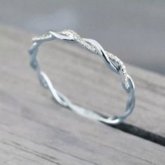 a white gold wedding band with twisted leaves on the side, sitting on a wooden surface