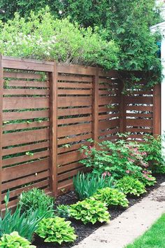 a wooden fence surrounded by plants and flowers