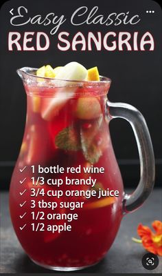 a pitcher filled with red sangria sitting on top of a table