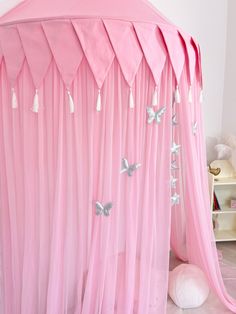 a pink canopy bed with white butterflies on the top and bottom, in a child's bedroom