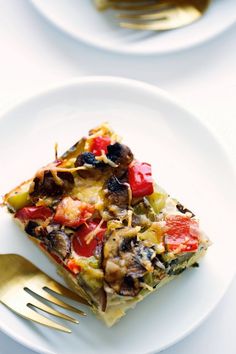 a slice of vegetable pizza on a white plate with a gold fork next to it