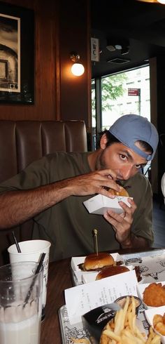 a man sitting at a table eating a sandwich and french fries in front of him