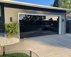 a car is parked in front of a house with a garage door open and landscaping around it