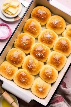 a pan filled with rolls covered in powdered sugar next to butter and other ingredients