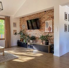 a living room filled with furniture and a flat screen tv mounted on a brick wall