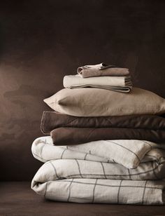 a stack of folded linens and blankets on top of each other in front of a dark background