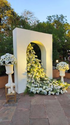 white flowers and greenery are arranged around an arch