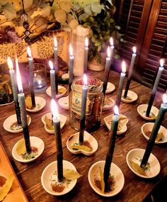 a table topped with lots of white plates filled with food and lit candles on top of them