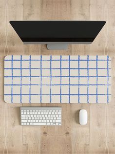 an overhead view of a computer keyboard, mouse and monitor on a wooden desk with a plaid pattern