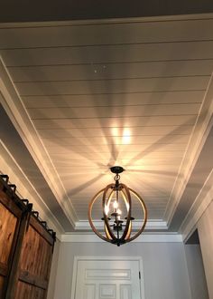 a chandelier hanging from the ceiling in a room with white walls and wood paneling