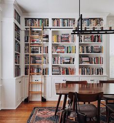 a dining room table and chairs with bookshelves in the background