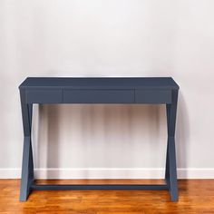 a blue table sitting on top of a hard wood floor next to a white wall