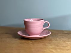 a pink coffee cup and saucer on a wooden table