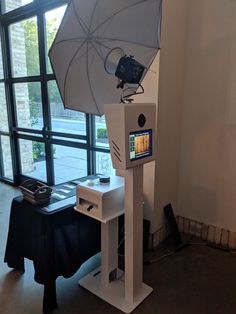 a camera set up in front of a window with an open umbrella on the stand