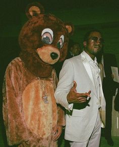 a man in a bear suit standing next to a person wearing a white blazer