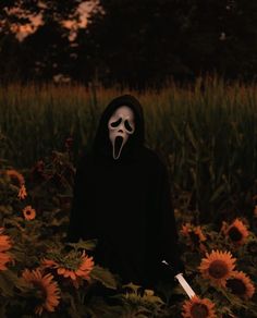 a person wearing a mask and holding a knife in a field of sunflowers