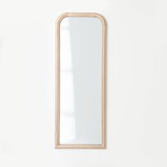 a wooden mirror hanging on the wall next to a white vase and flower pot in front of it