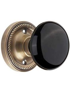 an antique brass door knob with black glass on the front and side, isolated against a white background