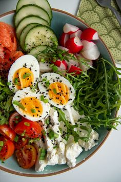 a plate with eggs, tomatoes, cucumbers and other vegetables